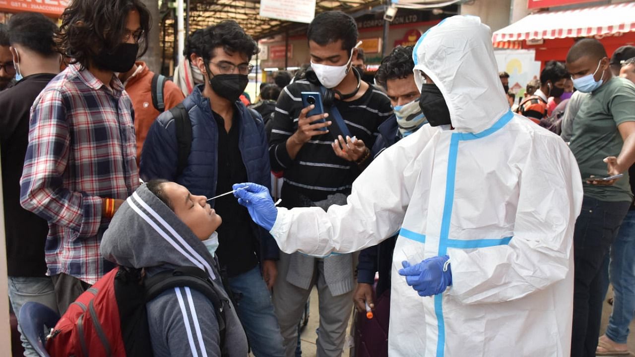 A health worker collects swab samples at KSR Bengaluru railway station on Monday. Credit: DH Photo/BK Janardhan