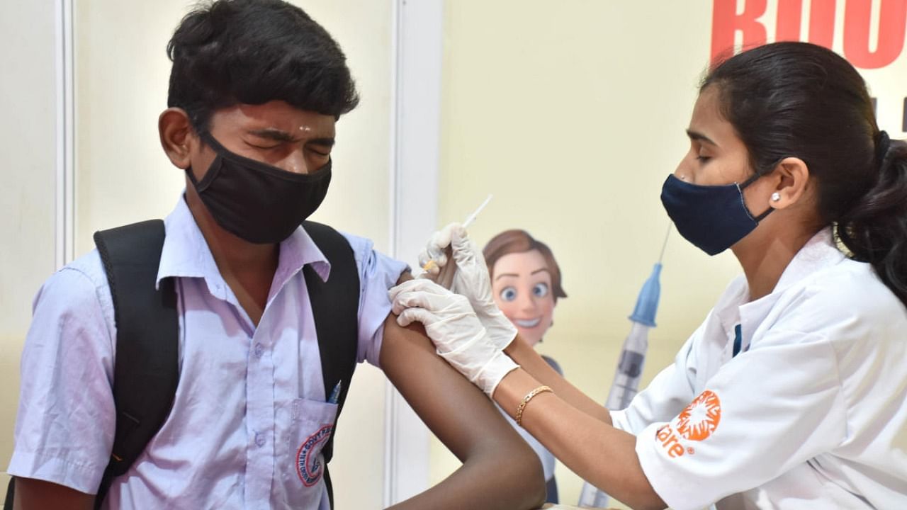 A health worker administers a dose of Covid-19 vaccine to a student during the COVID-19 vaccination drive under the age of 15 to 18 at a government school at Malleshwara in Bengaluru. Credit: DH Photo