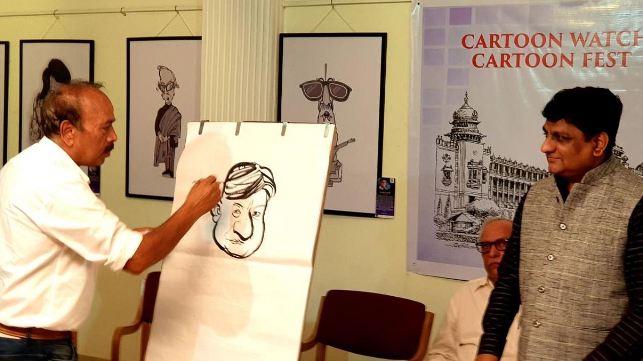 Veteran cartoonist Gujjarappa captures 'Cartoon Watch' editor Triambak Sharma on canvas at the Indian Cartoon Gallery in Bengaluru. Credit: DH Photo