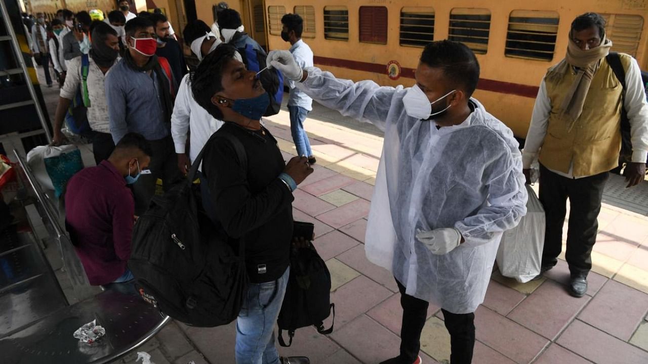 A medical staff takes a swab sample of a man for an RT-PCR test during a Covid-19 coronavirus screening as passengers arrive at a railway platform in Mumbai. Credit: AFP Photo