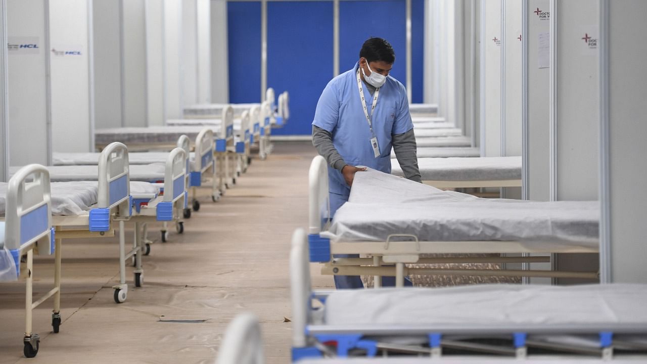 A worker prepares a bed for Covid patients in Commonwealth Games Village in view of the Omicron cases, in New Delhi. Credit: PTI File Photo