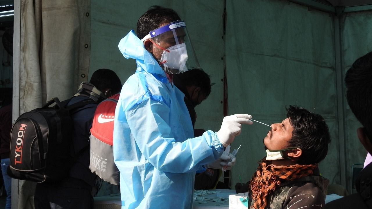 A healthcare worker collects a swab sample of a man for the Covid-19 test in view of rising Omicron cases, at Anand Vihar in New Delhi on Tuesday on January 5, 2022. Credit: IANS Photo