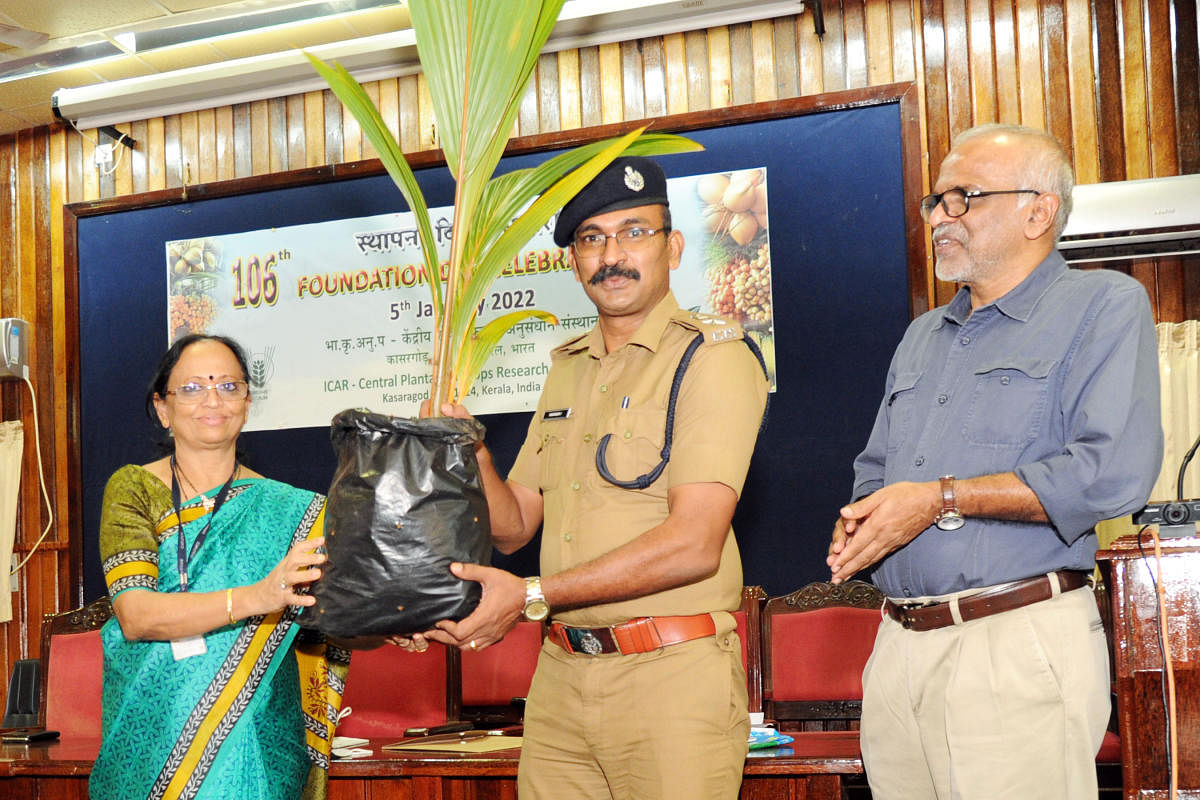 Acting Director of ICAR-CPCRI Dr Anitha Karun hands over a coconut seedling to Cheemeni Open prison Superintendent Sudheer T at PJ Hall in CPCRI in Kasaragod on Wednesday.