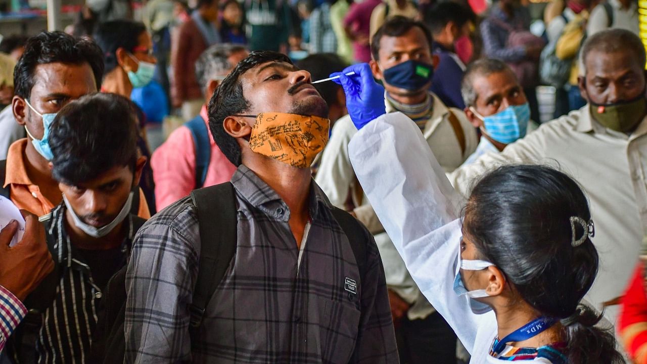 A Brihanmumbai Municipal Corporation (BMC) health worker collects swab samples of outstation passengers for Covid-19 test at the CSMT Station, amid concern over rising Omicron cases, in Mumbai, Wednesday, January 5, 2022. Credit: PTI Photo