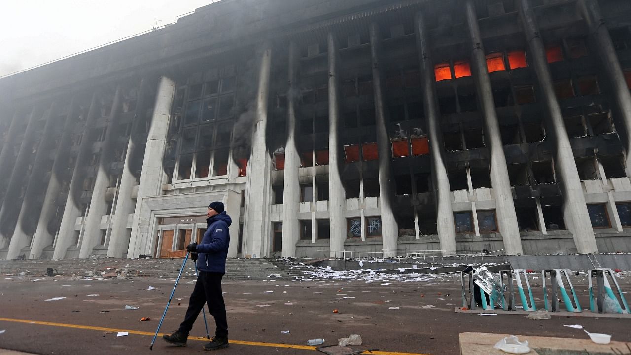 A man stands in front of the mayor's office building which was torched during protests triggered by fuel price increase in Almaty, Kazakhstan. Credit: Reuters Photo