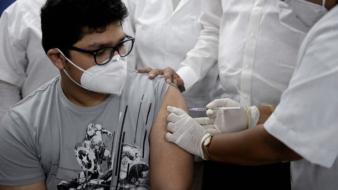 A health worker inoculates a youth with a Covid-19 vaccine during a vaccination drive for people in the 15-18 age group, at a primary health centre in Hyderabad. Credit: AFP Photo