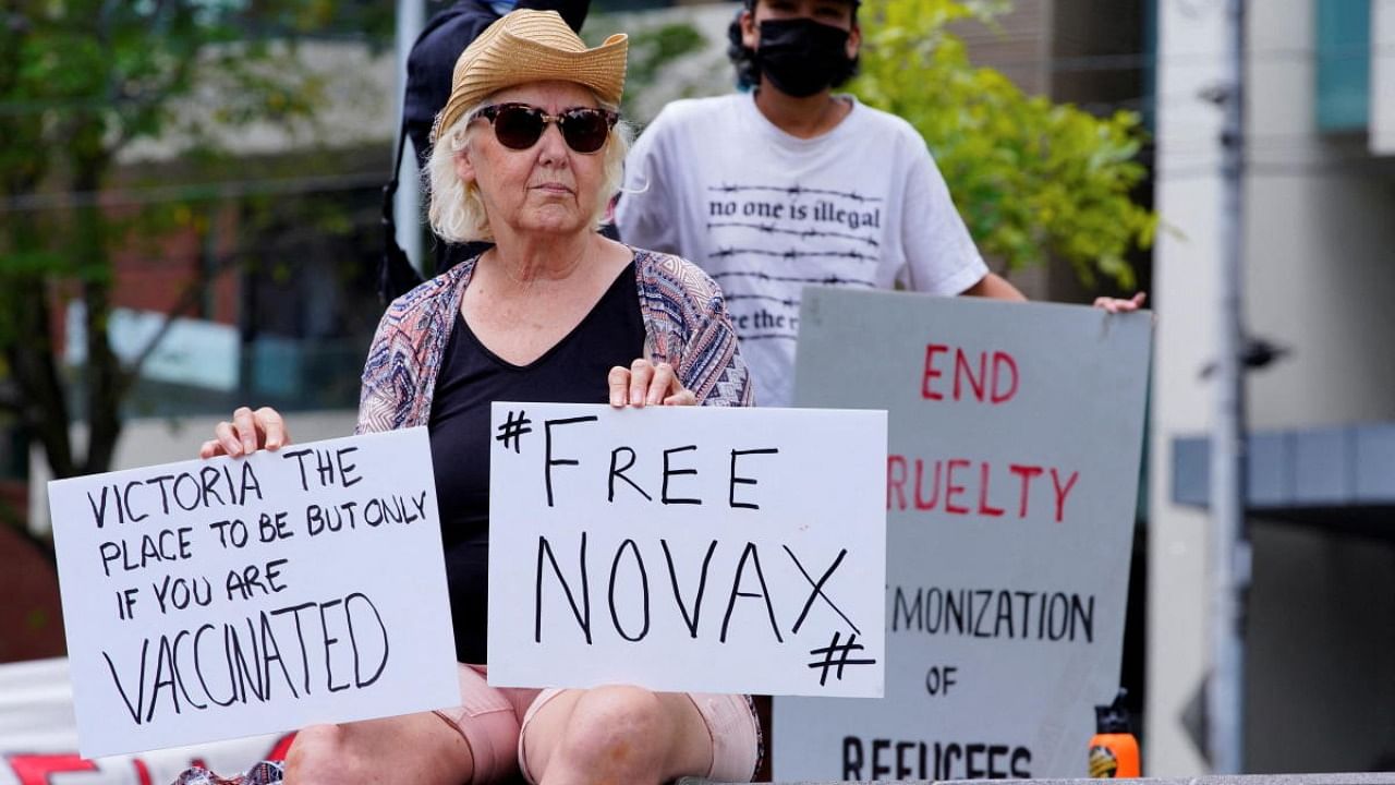 A protestor holds signs outside Park Hotel, where Serbian tennis player Novak Djokovic is believed to be living, in Melbourne. Credit: Reuters Photo