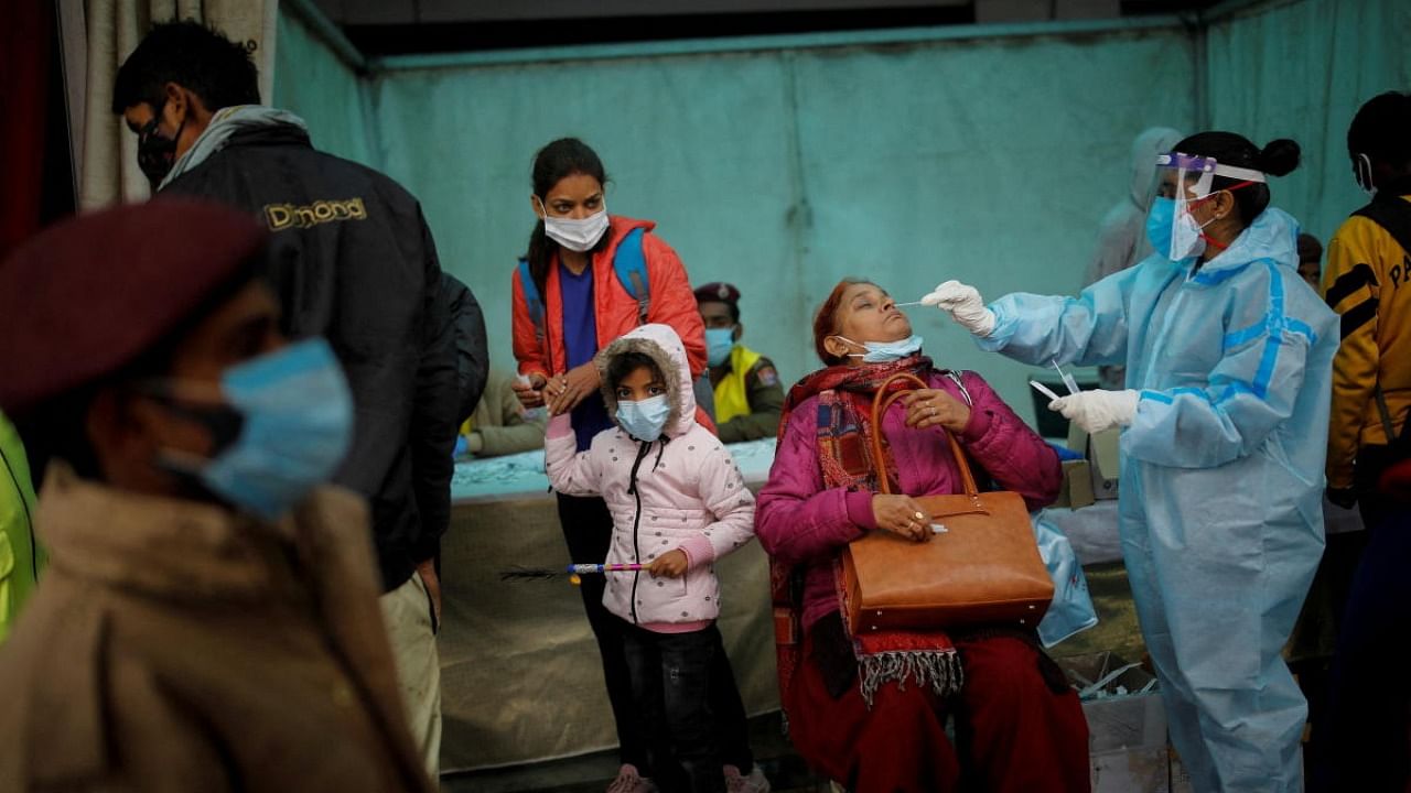 A healthcare worker collects a coronavirus disease (COVID-19) test swab sample from a woman amidst the spread of the disease, at a railway station in New Delhi, India, January 5, 2022. Credit: Reuters Photo