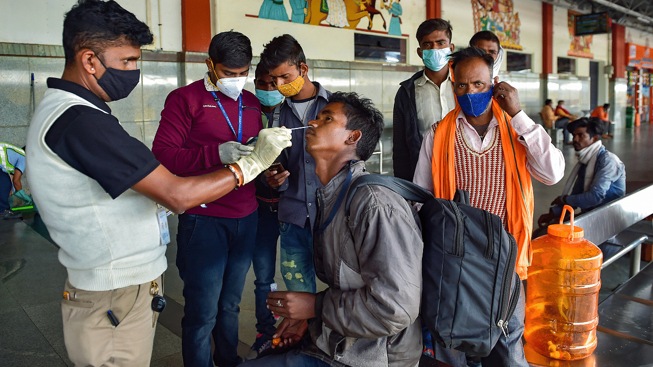  A health worker collects swab sample of a passenger for Covid-19 test, amid fear of spread of the Omicron variant of Covid-19. Credit: PTI Photo
