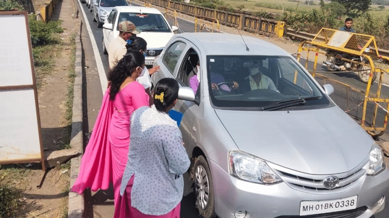 Police and Health personnel check RT-PCR test reports of passengers entering the district near Kognoli check post in Nippani taluk of Belagavi district. Credit: DH Photo