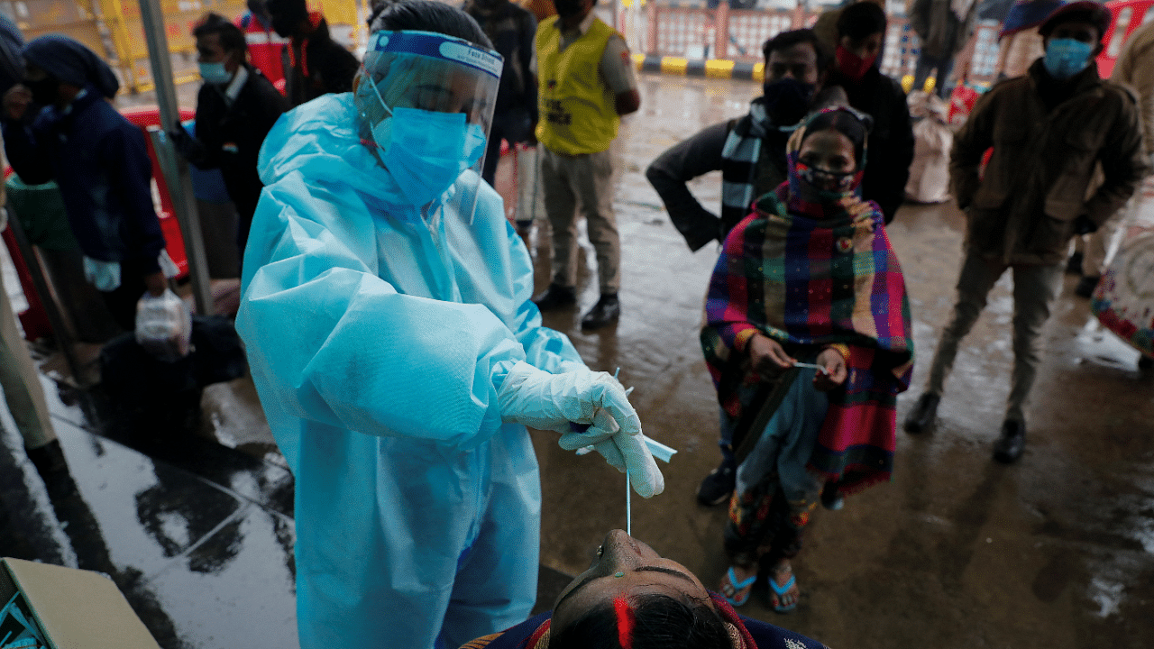 Healthcare worker collects COVID-19 test swab samples from people at a railway station in New Delhi. Credit: Reuters Photo