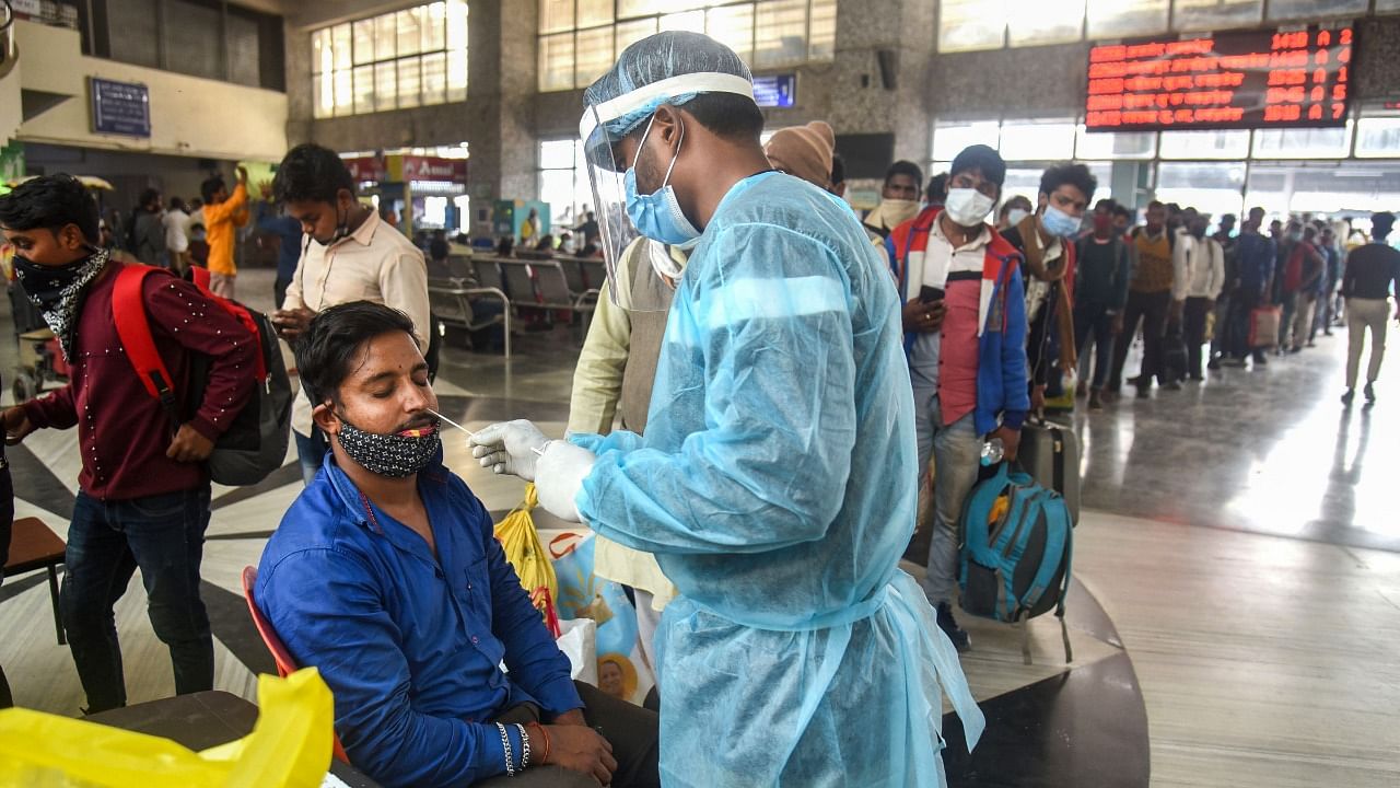 A healthcare worker collects a swab sample of a passenger for Covid-19 test, at Bandra Terminus, in Mumbai. Credit: PTI Photo