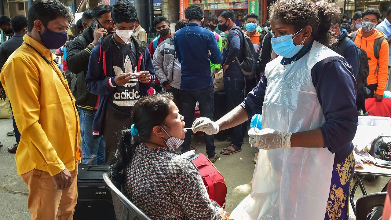 A health worker collects swab sample of a passenger for Covid-19 test, amid fear of spread of the Omicron variant, at Krantiveer Sangoli Rayanna (KSR) railway station in Bengaluru. Credit: PTI Photo