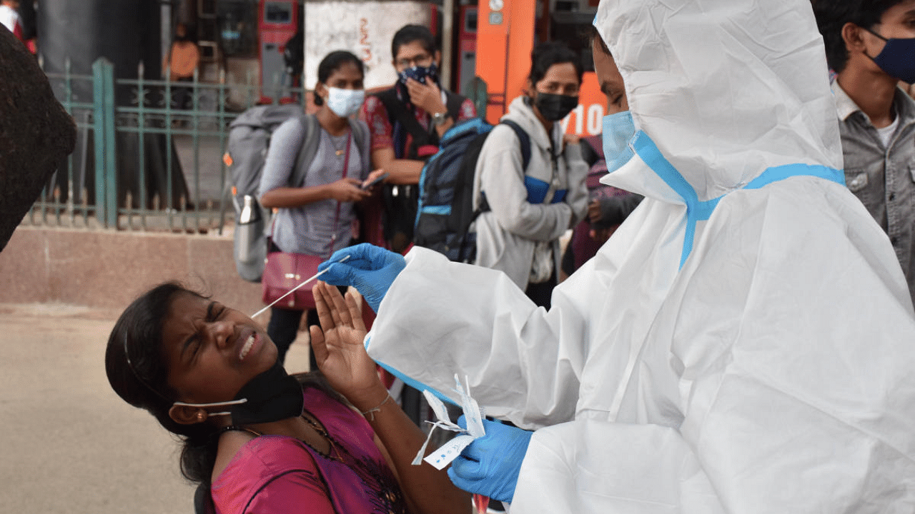 A health worker collects samples for Covid testing at the KSR railway station on Saturday. Credit: DH Photo