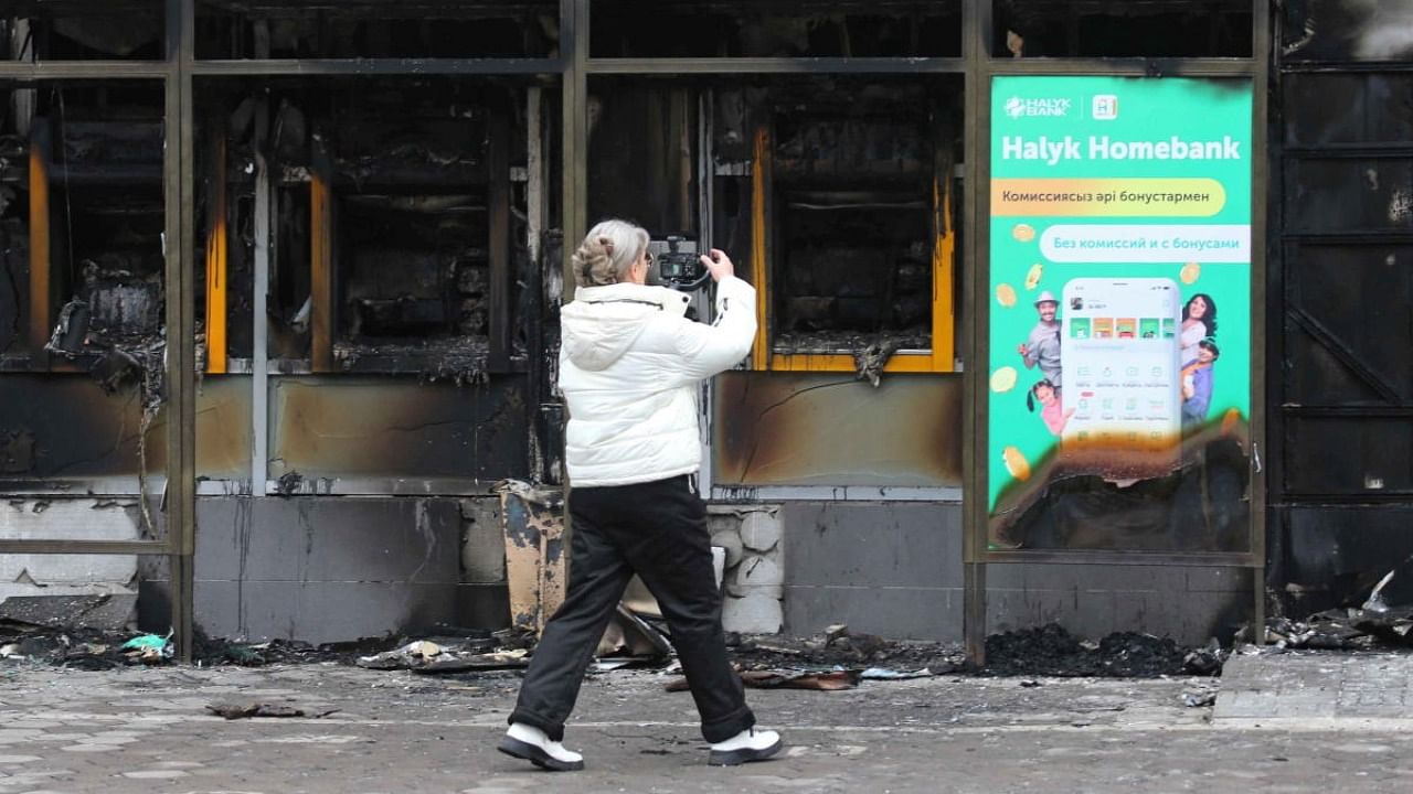 A woman films a building, which was burnt during mass protests triggered by fuel price increase, in Almaty. Credit: Reuters photo