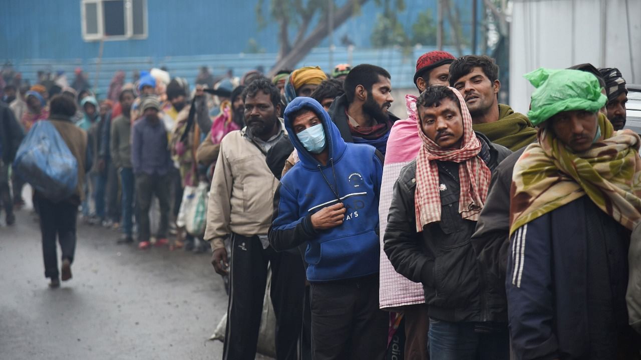 Homeless people and migrant labourers stand in a queue to collect free cooked food, during the weekend curfew imposed by the Delhi government to curb the spread of Covid-19, in New Delhi, Saturday, January 8, 2022. Credit: PTI Photo