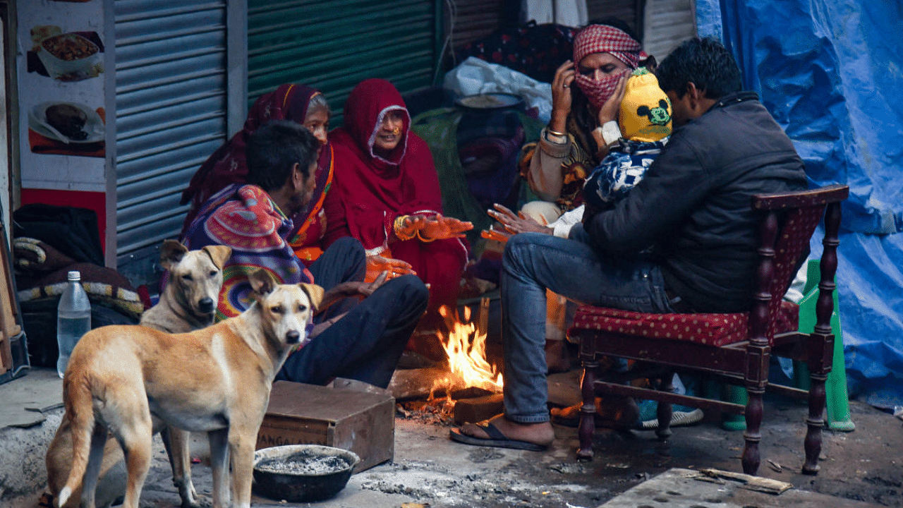 Labourers warm themselves with a bonfire at Karol Bagh market, during the weekend curfew imposed by the Delhi government to curb the spread of Covid-19. Credit: PTI Photo