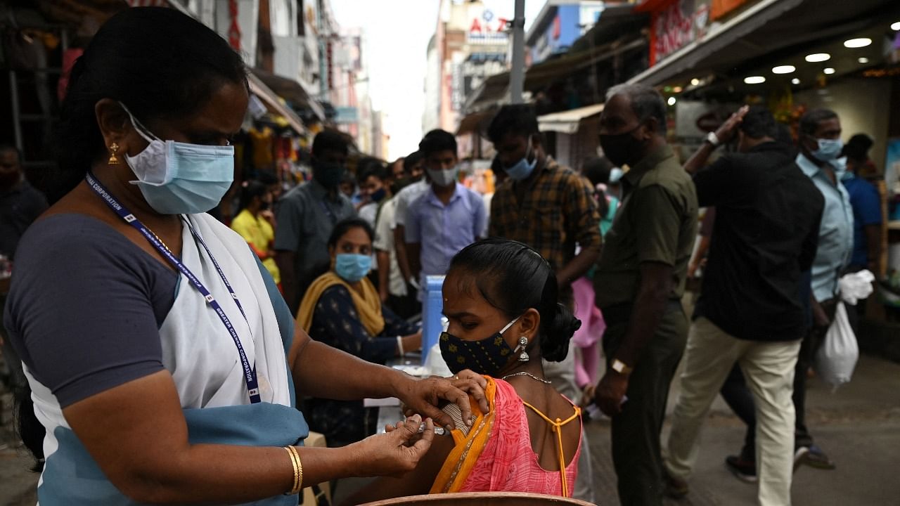 A health worker inoculates a woman with a dose of vaccine against the Covid-19 coronavirus during a vaccination drive. Credit: AFP Photo