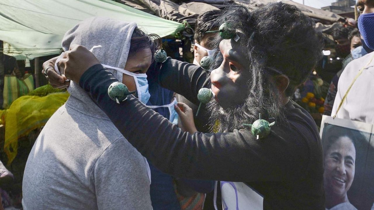 A volunteer requests a commuter to wear facemask as Covid-19 cases surge across the country, in Howrah. Credit: PTI Photo