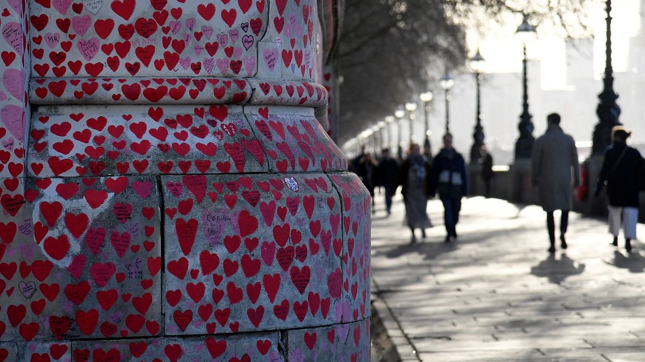 People walk beside the National Covid Memorial Wall, a dedication of thousands of hand-painted hearts and messages for those in the UK who have died from Covid-19, which this weekend passed 1,50 000 according to official figures, amid the coronavirus disease pandemic in London, Britain, January 9, 2022. Credit: Reuters Photo