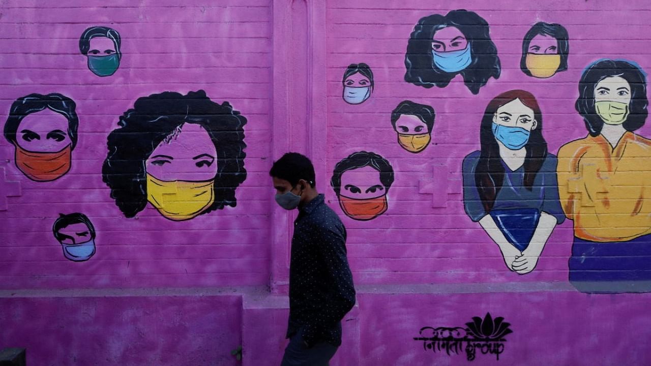 A man wearing a protective face mask walks past a mural on a street, amidst the spread of the coronavirus disease in Mumbai, India, January 10, 2022. Credit: Reuters Photo