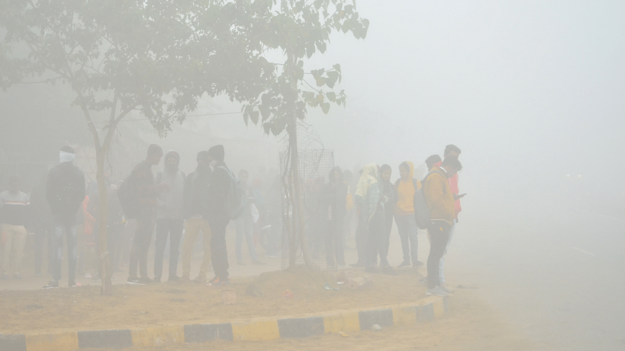 Students wait for a bus amid low visibility due to fog on a cold winter morning, at Fatehpur. Credit: PTI Photo