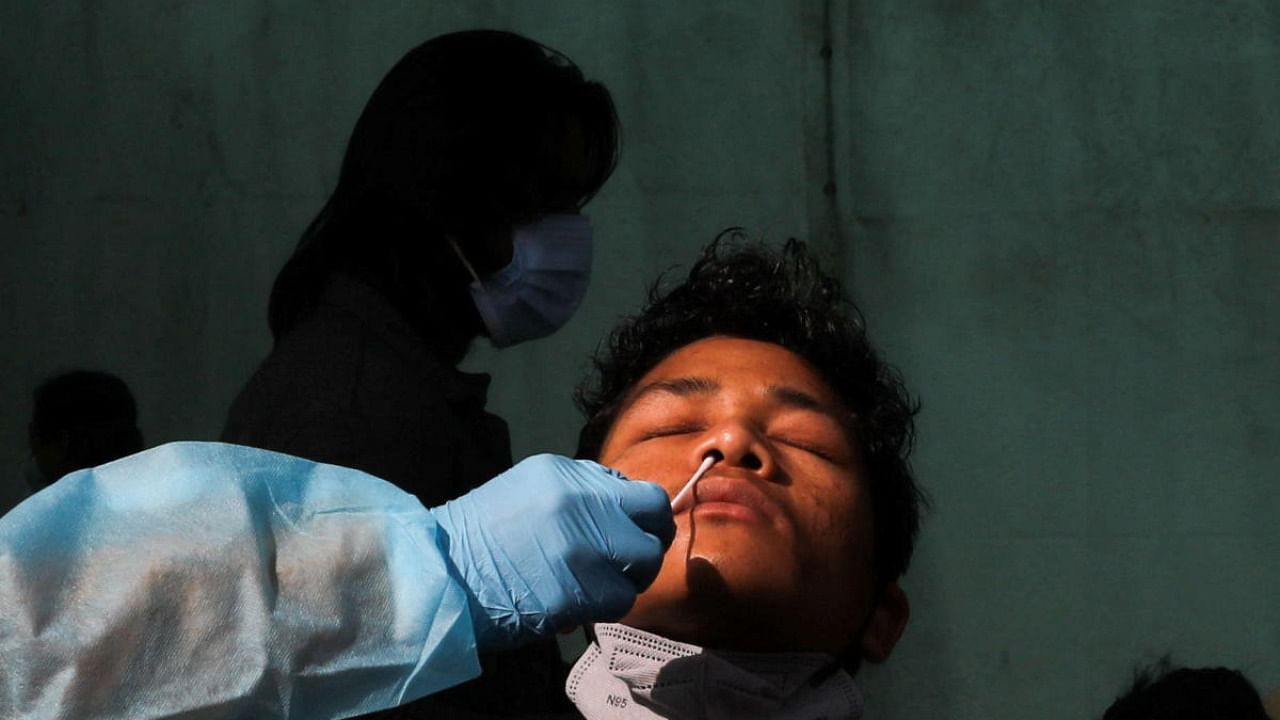 A healthcare worker collects a coronavirus disease test swab sample from a man, amidst the spread of the disease, at a railway station in New Delhi, India, January 11, 2022. Credit: Reuters Photo