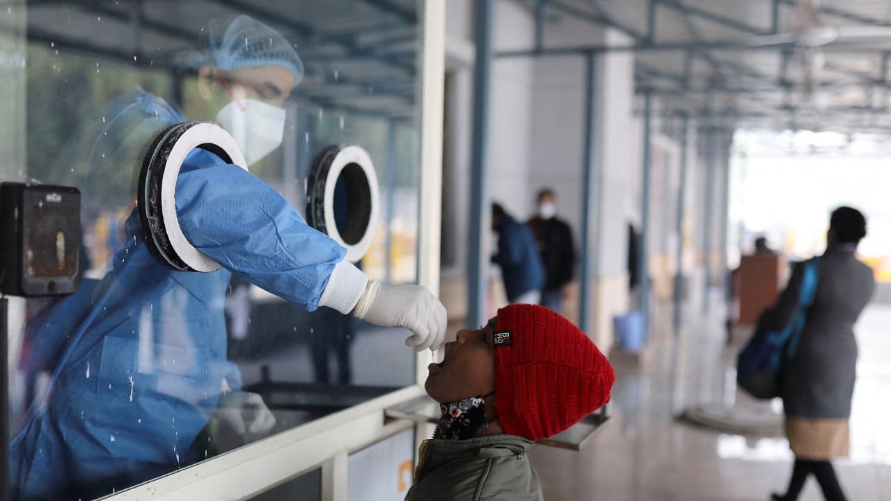 A healthcare worker collects a test swab sample from a child amidst the spread of the coronavirus disease, at a testing centre inside a hospital in New Delhi. Credit: Reuters Photo