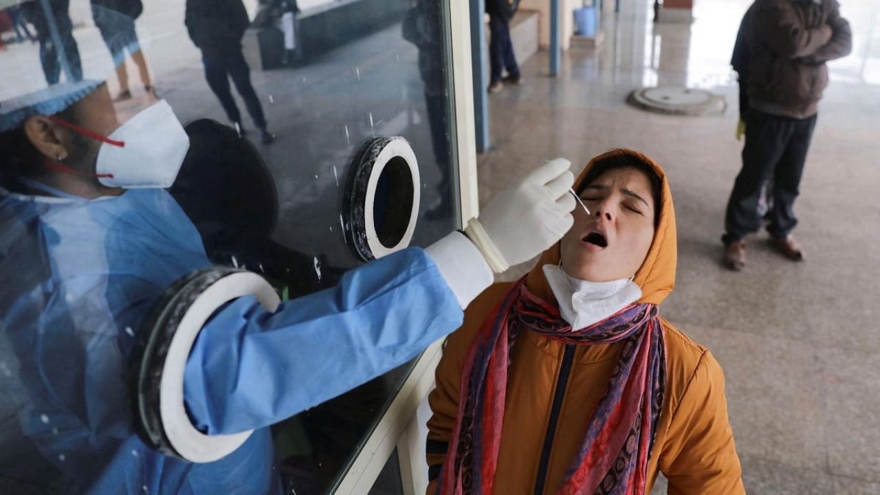 A healthcare worker collects a test swab sample from a woman amidst the spread of Covid-19 at a testing centre inside a hospital in New Delhi. Credit: Reuters photo