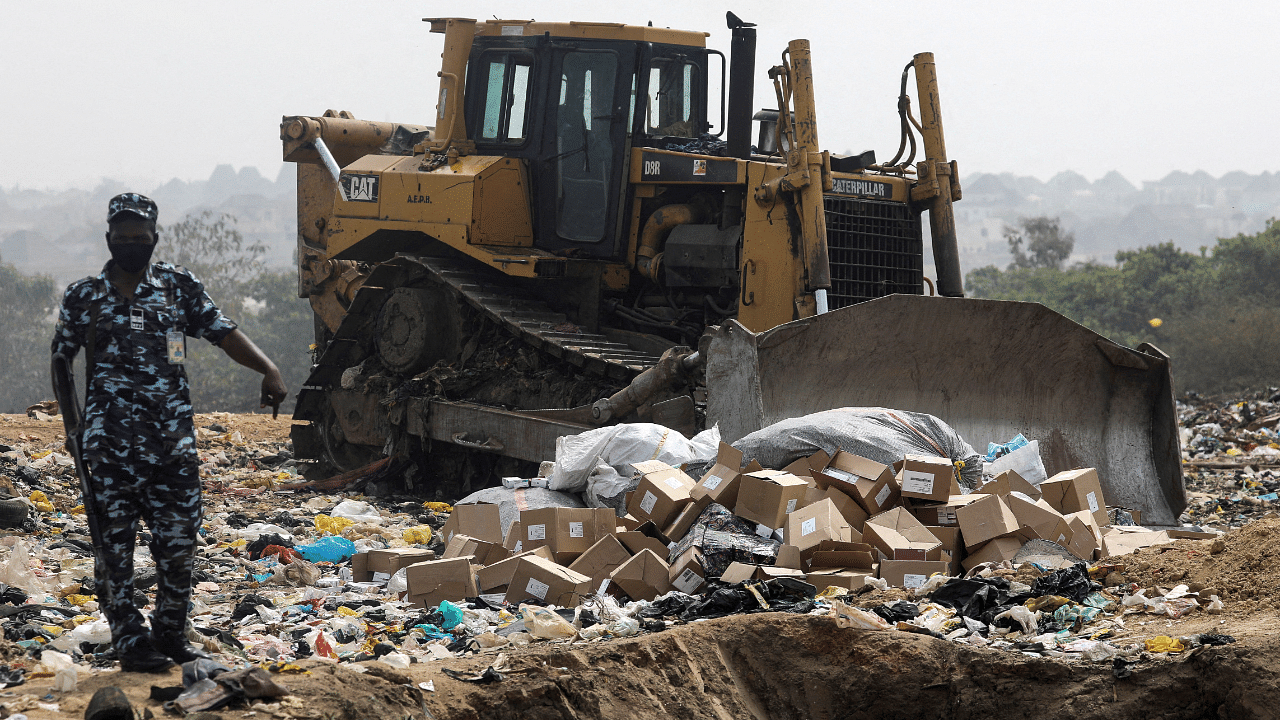  A police officer stands next to boxes of expired AstraZeneca coronavirus disease vaccines at the Gosa dump site in Abuja, Nigeria. Credit: Reuters Photo