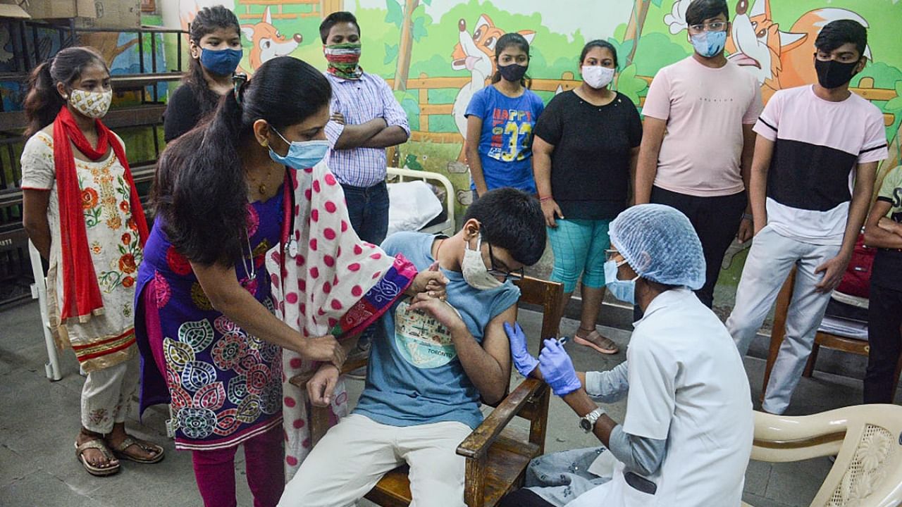 A healthworker administers a dose of Covid-19 vaccine to a teenager during a vaccination drive for 15-18 years age group, at a school in Thane. Credit: PTI Photo