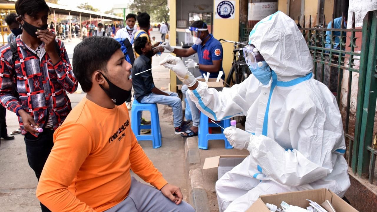 A health worker collects swab samples for Covid-19 test at the KSR Railway station in Bengaluru. Credit: DH Photo