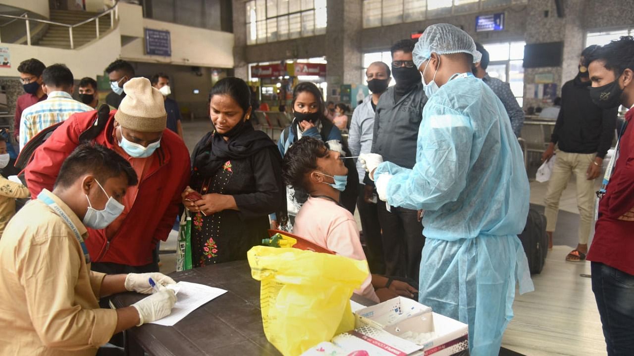 A healthcare worker collects swab sample of passengers for Covid-19 test, at Bandra Terminus, in Mumbai. Credit: PTI Photo