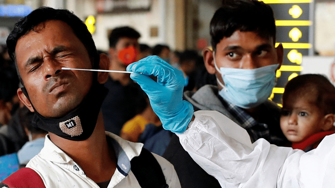 A man reacts as a health worker collects a swab sample during a rapid antigen testing campaign for coronavirus disease, at a railway station in Mumbai. Credit: Reuters Photo