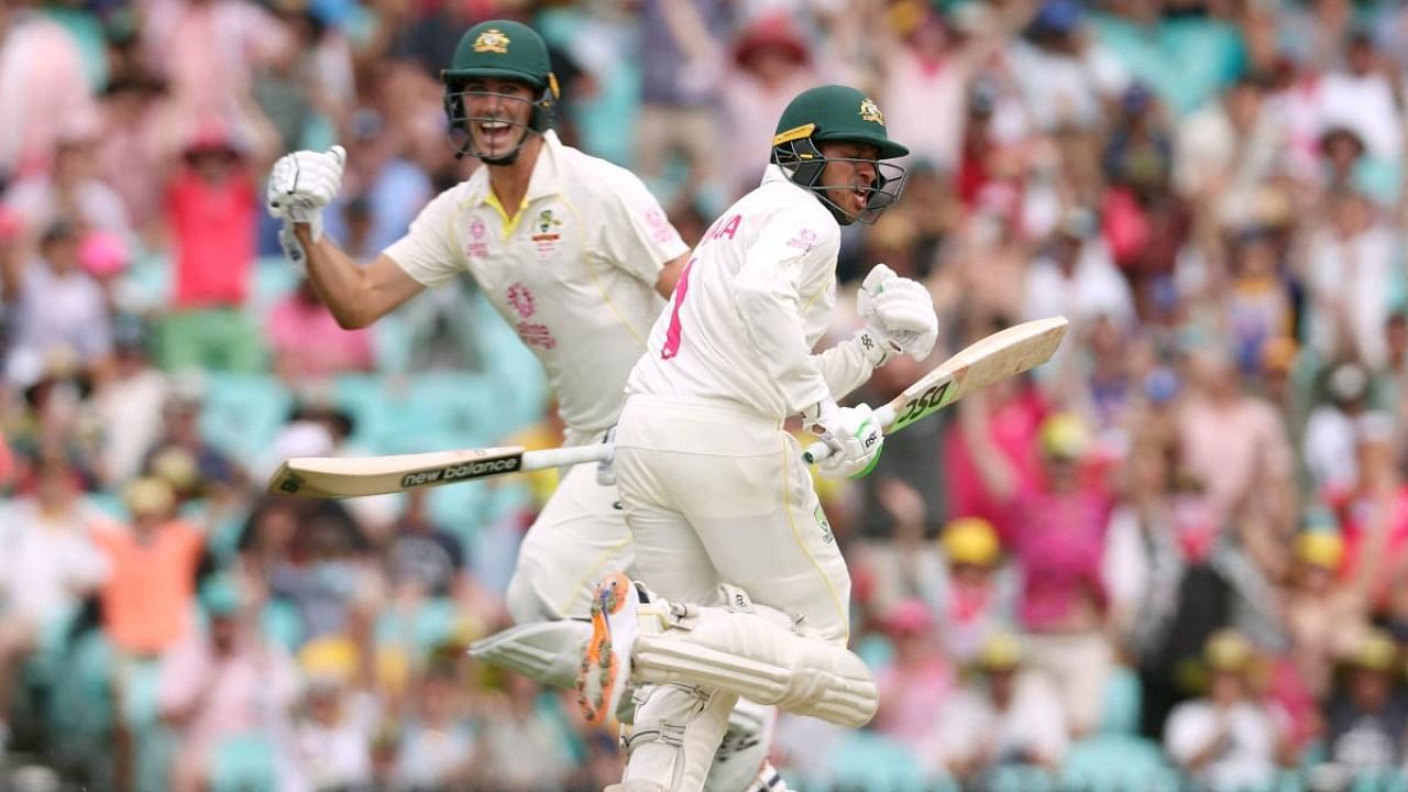 Australia's Usman Khawaja (R) celebrates as he runs to complete his century (100 runs) with teammate Pat Cummins on day two of the fourth Ashes cricket Test match between Australia and England at the Sydney Cricket Ground (SCG) on January 6, 2022. Credit: AFP Photo