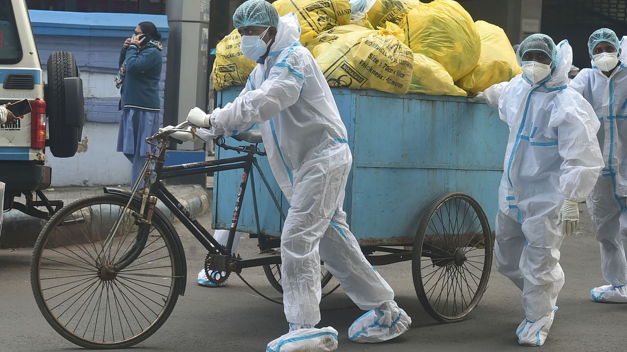 Workers carry Covid waste from a State Government-run Covid hospital for dumping, in Kolkata. Credit: PTI Photo