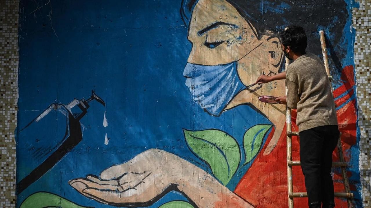 An artist paints a mural based on Covid-19 coronavirus safety protocols on the walls of an underpass during an ongoing weekend curfew imposed in New Delhi on January 16, 2022 to curb the spread of the Covid-19 coronavirus. Credit: AFP Photo