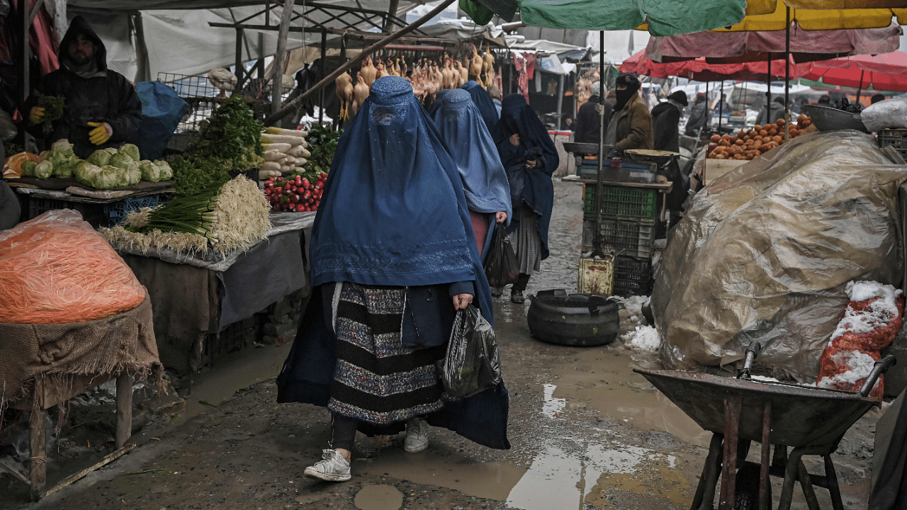 Burqa-clad women walk along a market on a cold day in Kabul. Credit: AFP Photo