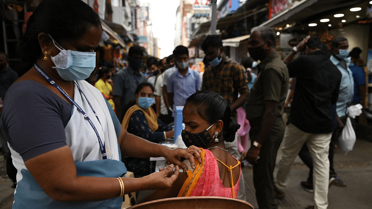 A health worker inoculates a woman with a dose of the Covishield vaccine against the Covid-19 coronavirus during a vaccination drive. Credit: AFP Photo