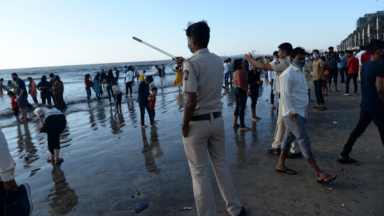 Policemen gestures as they try to disperse beachgoers to inforce newly imposed restrictions to curb the spread of the Covid-19 coronavirus at Juhu beach. Credit: AFP Photo