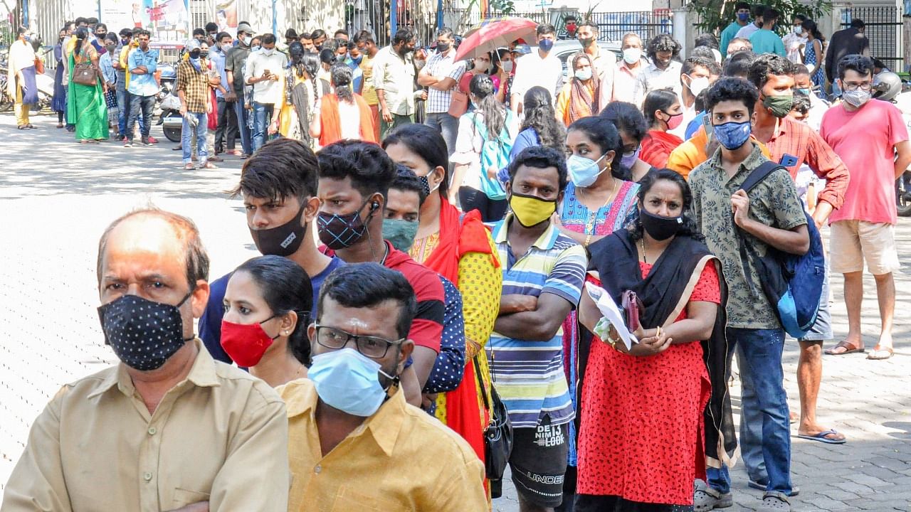 People stand in a queue as they wait to receive a dose of Covid-19 vaccine in Kochi. Credit: PTI File Photo