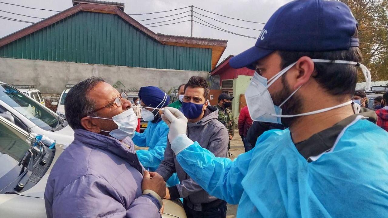  A health worker collects swab samples of a taxi driver for COVID-19 testing at a Taxi Stand in wake of spike in coronavirus cases, in Srinagar. Credit: PTI Photo