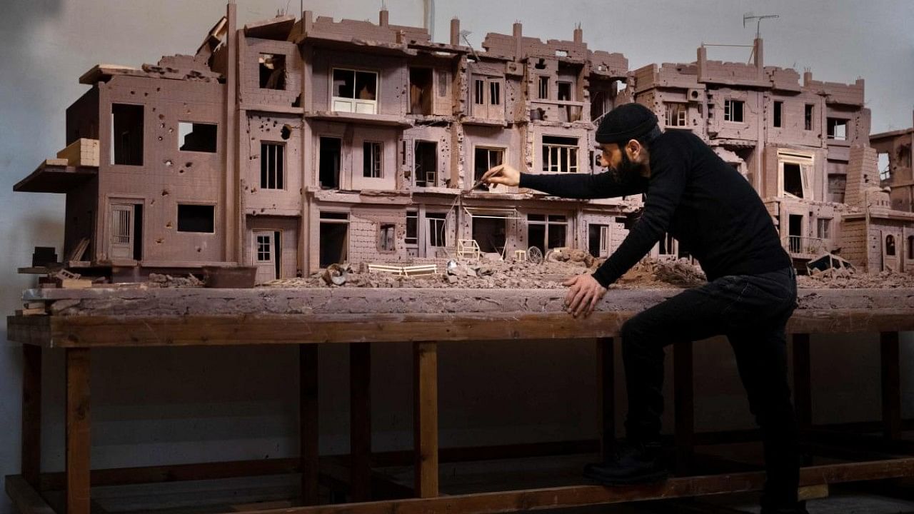 Syrian sculptor Khaled Dawwa works on a clay artpiece, representing a street in Syria destroyed by Syrian regime forces and their allies, during a photo session in his workshop in Vanves, near Paris. Credit: AFP Photo