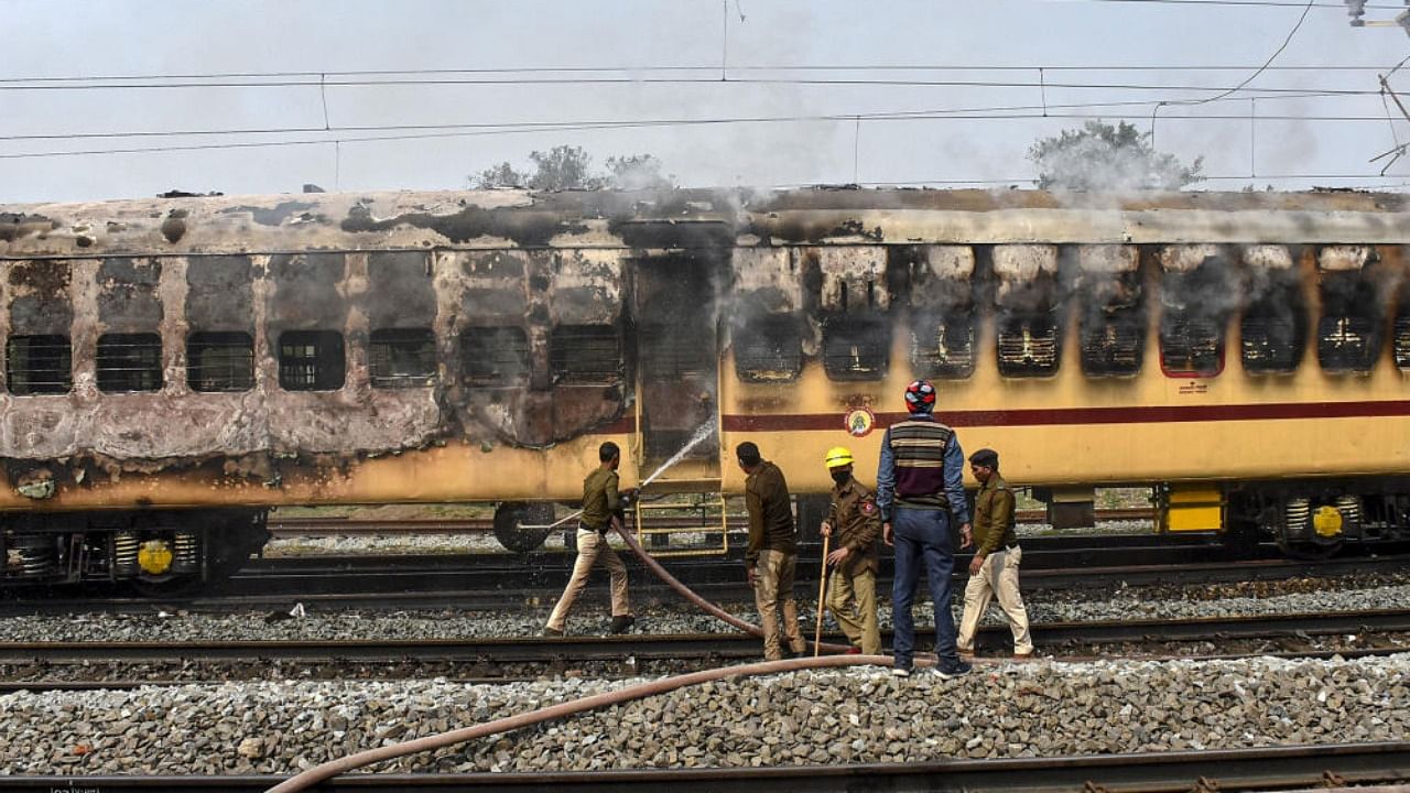 Railway Protection Force personnel try to douse the fire in a train set by the aspirants, during their protest over alleged erroneous results of Railway Recruitment Boards-Non Technical Popular Categories (RRB-NTPC) exams, at Gaya Junction railway station, Wednesday, January 26, 2022. Credit: PTI Photo
