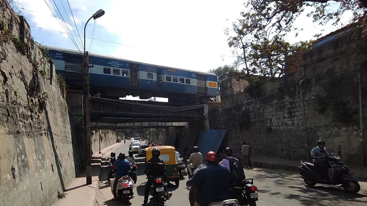 Motorists stop as a train passes by at the rail under bridge near Anand Rao Circle in Bengaluru. Credit: DH Photo