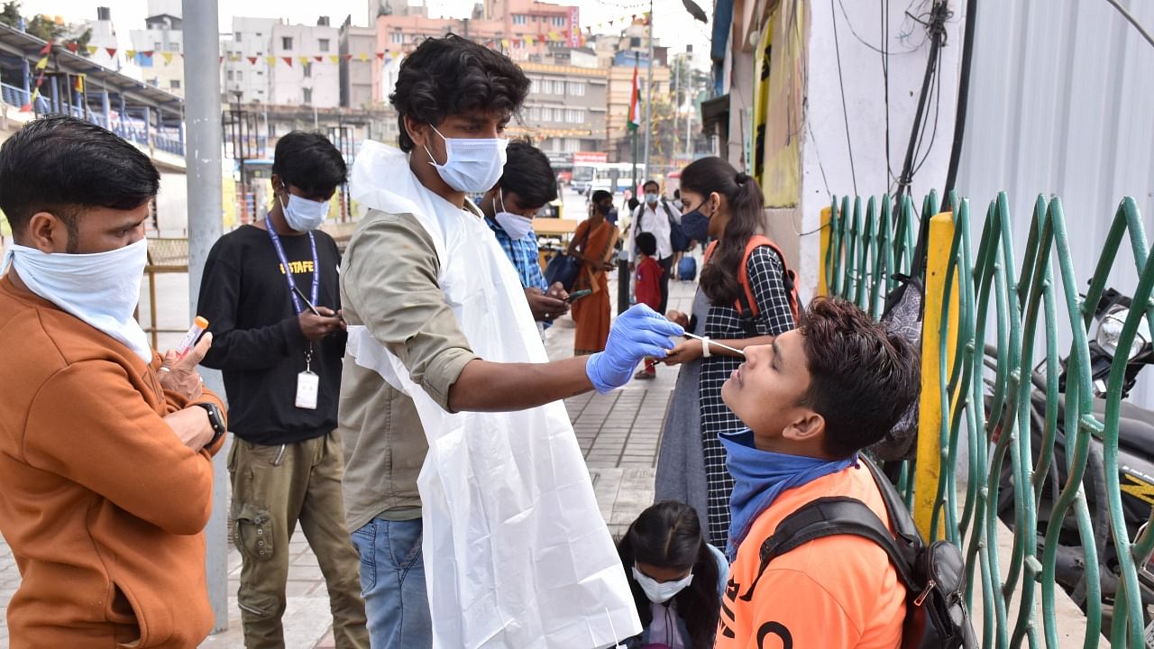 A health worker draws a swab sample from a passenger for the Covid test, at KSRTC bus stand in Bengaluru on Wednesday. Credit: DH Photo/B K Janardhan