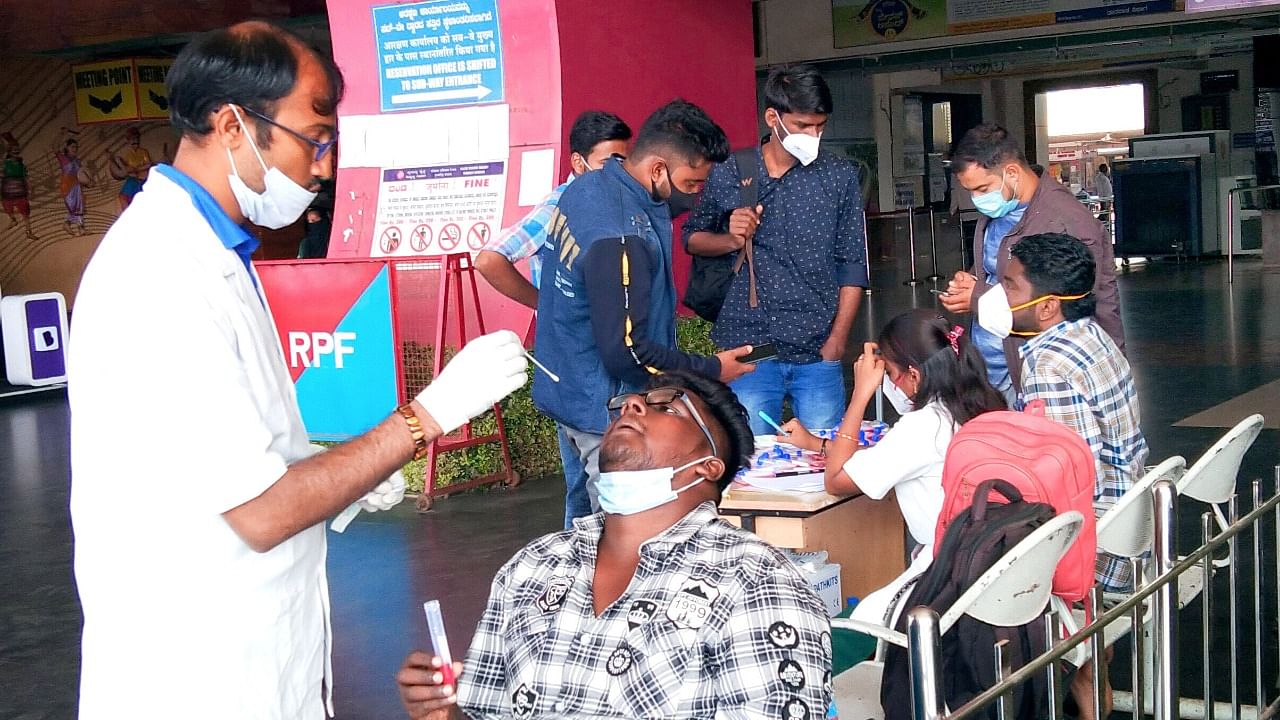 A health worker collects a sample for Covid-19 testing at Hubballi Railway Station. Credit: DH File Photo