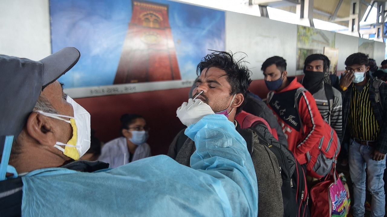 A health worker takes a swab sample from a passenger to test for the Covid-19 coronavirus at Kalupur Railway Station in Ahmedabad on January 25, 2022. Credit: AFP Photo