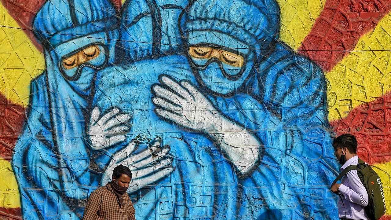 A pedestrian walks past a wall mural depicting health workers wearing Personal Protective Equipment (PPE) suits to spread awareness about the Covid-19 coronavirus in Mumbai on January 29, 2022. Credit: AFP Photo