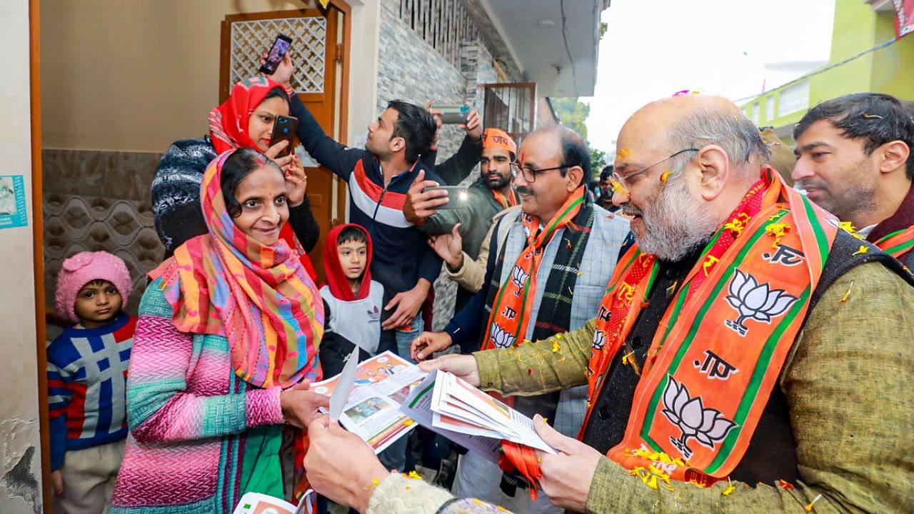 Union Home Minister Amit Shah gives a pamphlet to a woman during his door-to-door campaign ahead of Uttar Pradesh Assembly elections, in Kairana. Credit: PTI Photo